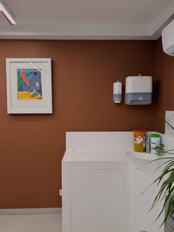 Treatment room at Demajo Medical with terracotta wall and framed abstract print