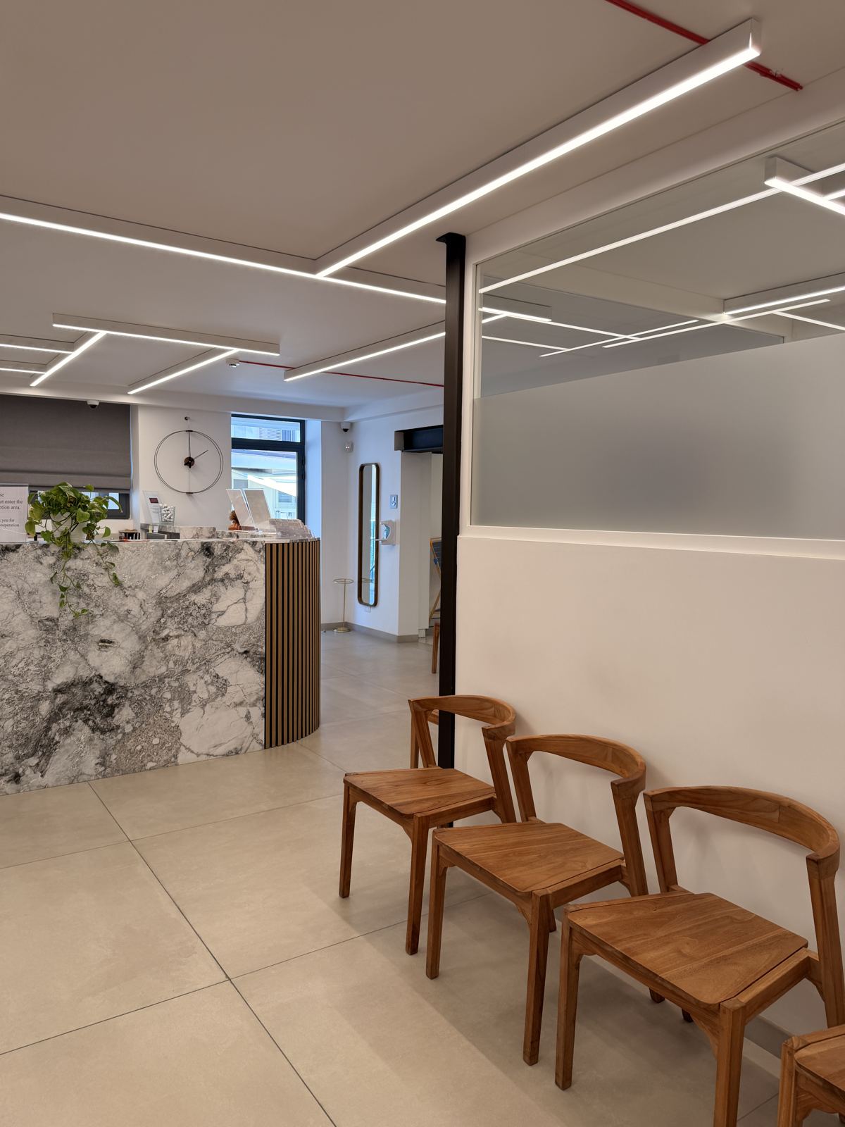 Teak chairs in the bright waiting area at Demajo Medical